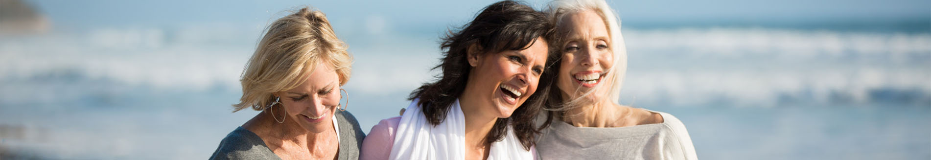 Three smiling mature women at the beach